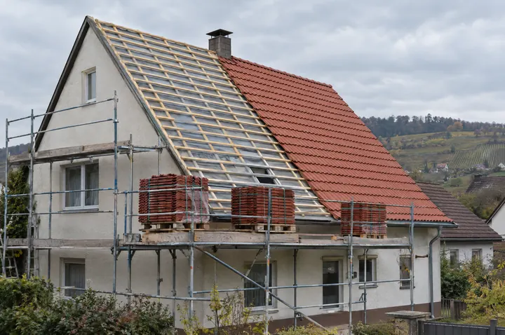 Symbolbild: Steildach während der Sanierung, eine Hälfte auf neuer Lattung, die andere mit neuen Tonziegeln eingedeckt