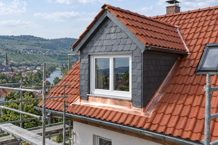 Symbolbild: neue Giebelgaube mit Schieferverkleidung und Kupferanschlüssen in einem Tonziegeldach, Remstal im Hintergrund