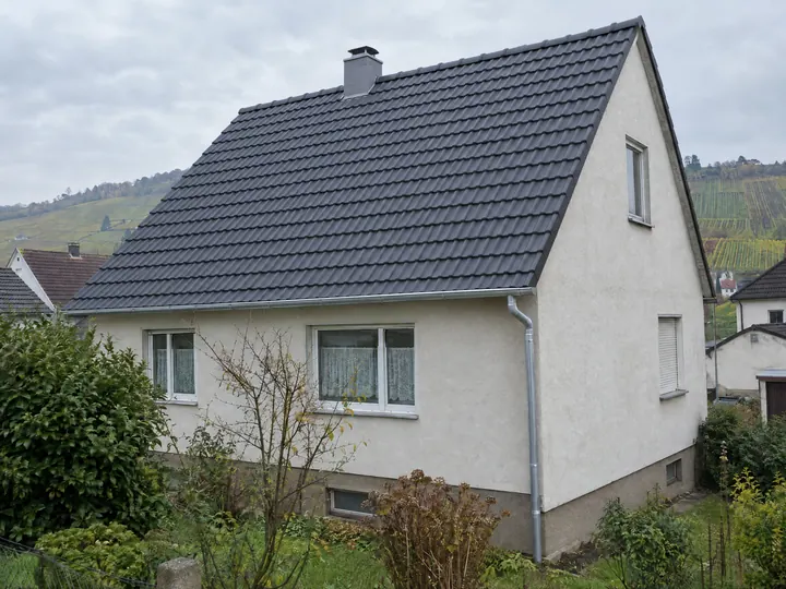 Symbolbild: dasselbe Satteldach mit neuen anthrazitfarbenen Ziegeln und neuer Rinne