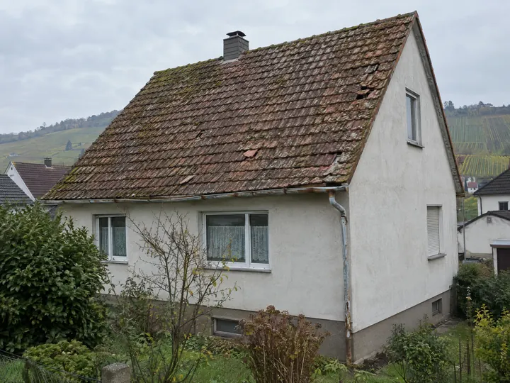 Symbolbild: Satteldach mit bemoosten, verrutschten Tonziegeln vor der Sanierung