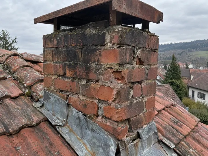 Symbolbild: Kamin mit bröckelnden Fugen und loser, korrodierter Verwahrung